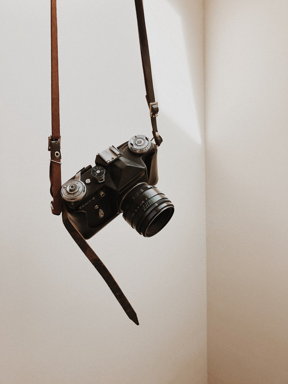 Macchina fotografica vintage appesa a una tracolla di pelle.