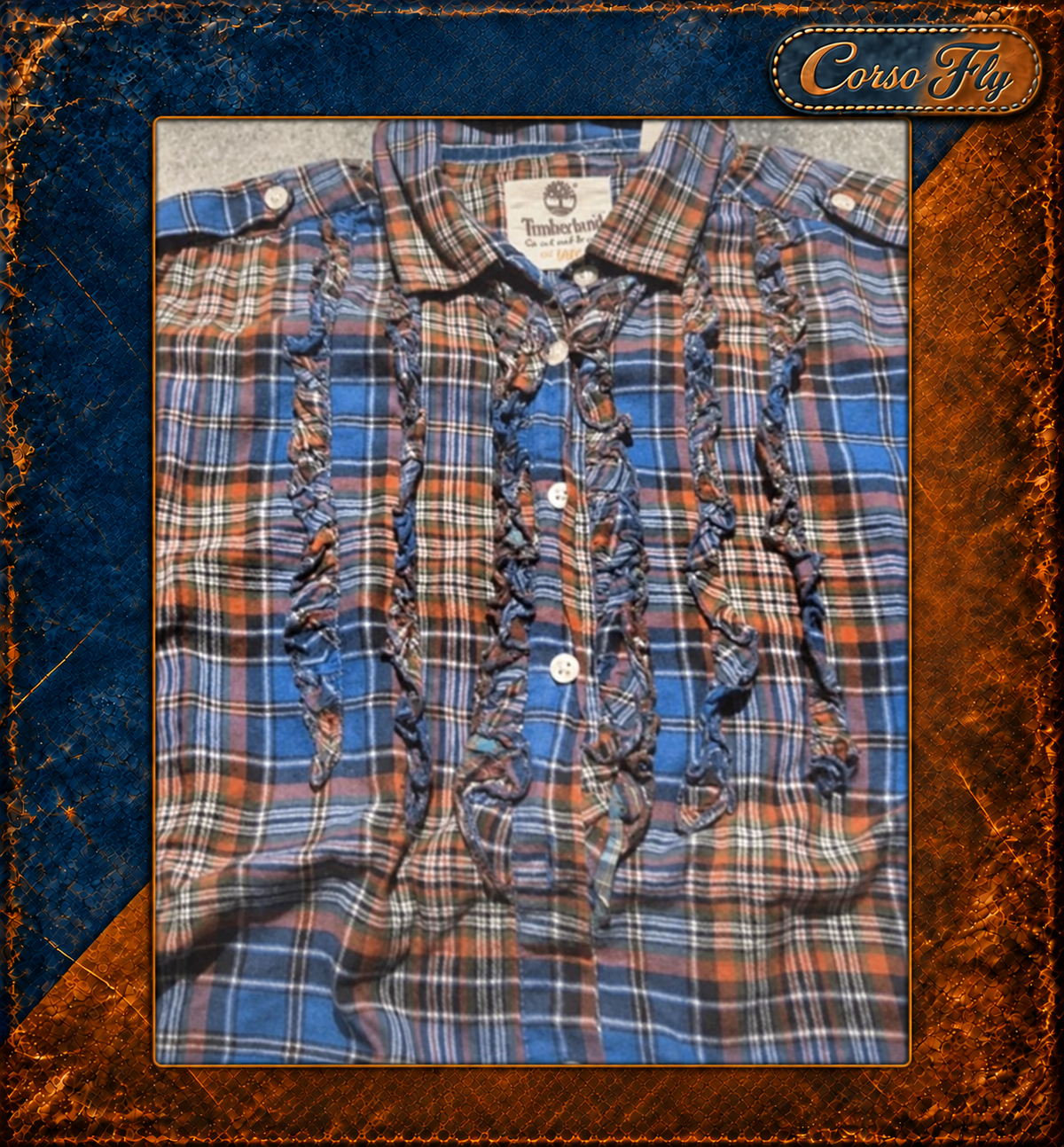 Dettaglio volant anteriori — camicia Timberland a quadri, sfondo Corso Fly